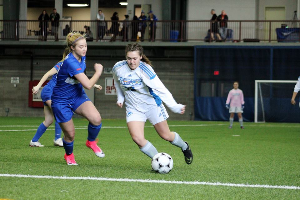 Womens indoor soccer player with ball against defender